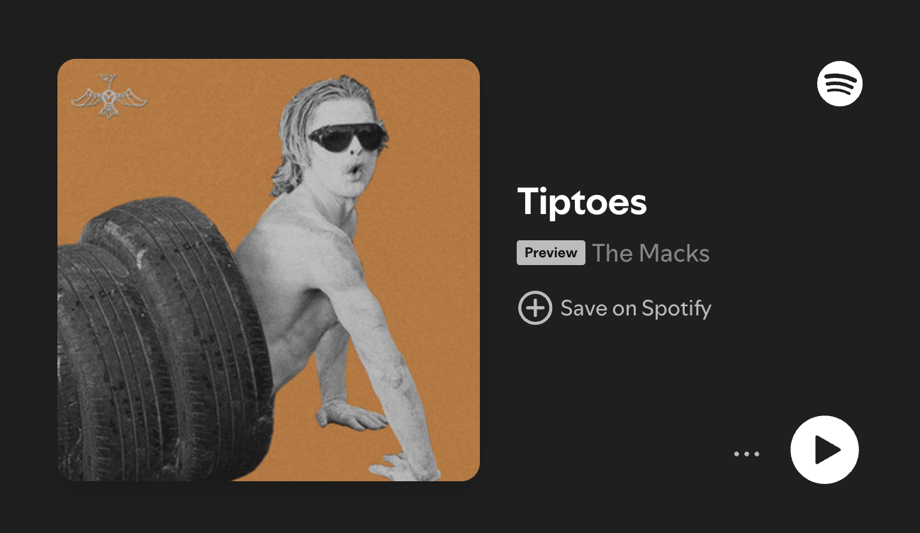 Picture of man painted white with sunglasses climbing out of a tire tunnel to promote The Macks new song "Tiptoes"